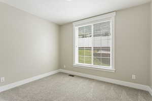 Empty room with a textured ceiling and carpet floors