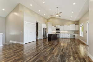 Kitchen featuring appliances with stainless steel finishes, high vaulted ceiling, a kitchen island with sink, and dark hardwood / wood-style floors