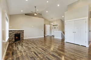 Unfurnished living room featuring a stone fireplace, high vaulted ceiling, hardwood / wood-style flooring, and ceiling fan