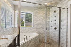 Bathroom with tile walls, vanity, and shower with separate bathtub