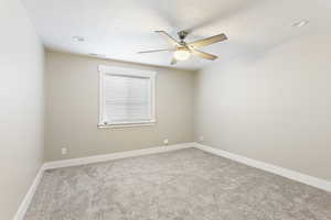 Carpeted spare room with ceiling fan and a textured ceiling