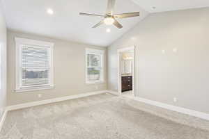 Unfurnished bedroom featuring light carpet, high vaulted ceiling, ceiling fan, and ensuite bath