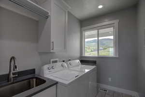 Laundry room with cabinets, tile flooring, washer and dryer, and sink