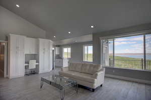 Living room featuring high vaulted ceiling and light wood-type flooring; open to kitchen and dining room