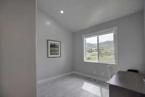 Office space/bedroom featuring lofted ceiling, light wood-type flooring, and a mountain view