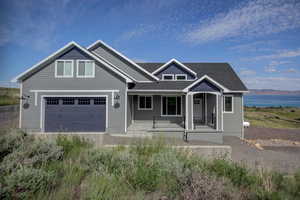 Craftsman-style house with a porch, a garage, and a water view