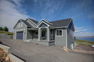 View of front facade featuring a water view, a garage, and covered porch