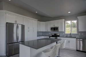 Kitchen featuring a center island, stainless steel appliances, white cabinetry, and sink