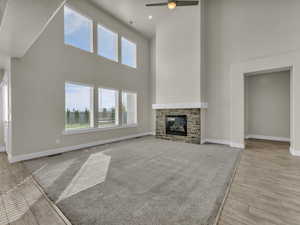 Unfurnished living room featuring a ceiling fan, baseboards, plenty of natural light, and a towering ceiling