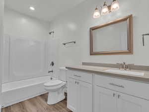 Full bath featuring vanity, bathing tub / shower combination, toilet, and wood finished floors