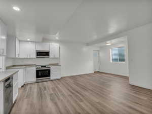 Kitchen with light countertops, light wood-style floors, stainless steel appliances, recessed lighting, and white cabinetry
