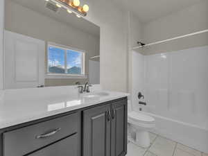 Bathroom featuring visible vents, vanity, marble finish floor, bathing tub / shower combination, and toilet