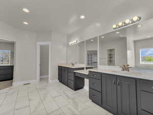 Primary Bedroom Full bath featuring two vanities, a sink, baseboards, marble finish floor, and recessed lighting