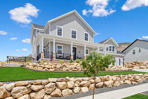 View of front of home with a garage, a front yard, and covered porch