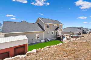 Back of property with a hot tub and a lawn