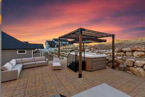 Patio terrace at dusk featuring a pergola, outdoor lounge area, and a hot tub