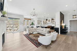 Living room with a notable chandelier, sink, light hardwood / wood-style floors, and a fireplace