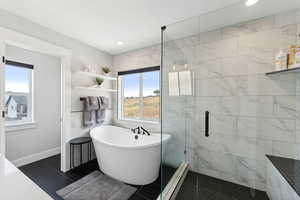 Bathroom with tile flooring, separate shower and tub, and tile walls