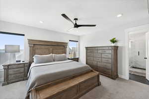 Carpeted bedroom featuring connected bathroom and ceiling fan