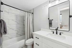 Full bathroom with vanity with extensive cabinet space, toilet, and shower / tub combo