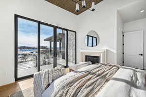 Bedroom featuring light hardwood / wood-style floors, access to exterior, wood ceiling, and vaulted ceiling