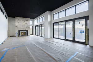 Unfurnished living room with a towering ceiling and a stone fireplace