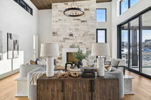 Living room featuring wood ceiling, light hardwood / wood-style floors, a high ceiling, and a notable chandelier