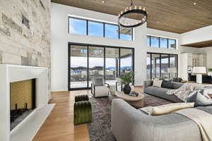 Living room with plenty of natural light, a large fireplace, light wood-type flooring, and a high ceiling