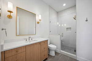 Bathroom featuring tile patterned flooring, vanity, toilet, and an enclosed shower