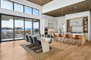 Dining space with a towering ceiling, light hardwood / wood-style floors, plenty of natural light, and wood ceiling