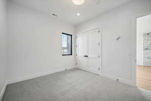 Unfurnished bedroom with light colored carpet and a closet