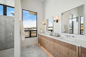 Bathroom featuring a wealth of natural light, a shower with door, and vanity