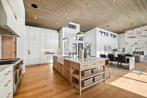 Kitchen with range with two ovens, a high ceiling, ventilation hood, and white cabinetry