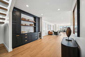 Bar featuring wine cooler, sink, and light hardwood / wood-style flooring