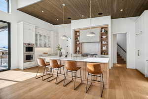 Kitchen featuring white cabinets, pendant lighting, light wood-type flooring, and plenty of natural light