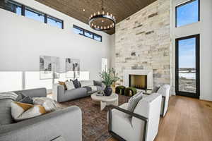 Living room with wood-type flooring, a fireplace, a high ceiling, and an inviting chandelier