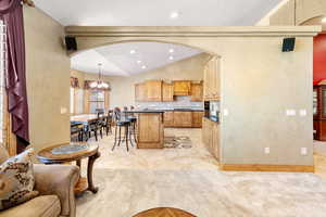 Kitchen with tasteful backsplash, pendant lighting, premium range hood, light colored carpet, and lofted ceiling