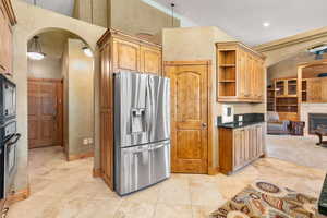 Kitchen featuring hanging light fixtures, high vaulted ceiling, stainless steel appliances, and light tile flooring