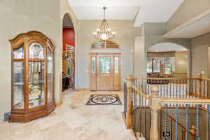 Tiled foyer with high vaulted ceiling and an inviting chandelier