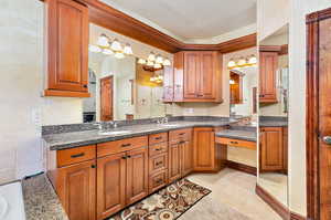 Primary bathroom with light tile flooring, pendant lighting, dark stone countertops, a textured ceiling, and sink