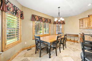 Tiled dining room with a chandelier, a textured ceiling, and vaulted ceiling