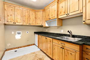 Laundry room featuring sink, a textured ceiling, and light tile flooring