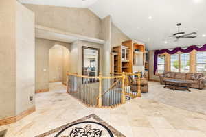 Hallway with high vaulted ceiling and light tile flooring