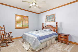 Carpeted bedroom featuring ornamental molding and ceiling fan