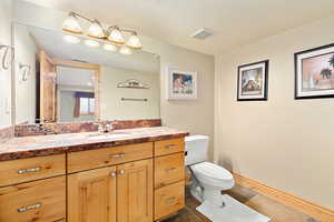 Bathroom with tile floors, a textured ceiling, toilet, and vanity