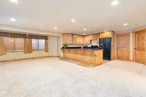 Kitchen featuring sink, light carpet, and black appliances