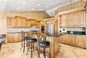 Kitchen with a kitchen island, stainless steel appliances, a breakfast bar area, high vaulted ceiling, and light tile floors