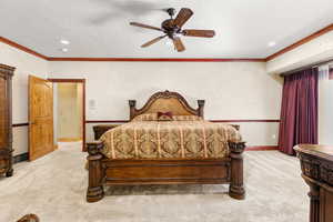 Primary bedroom with light carpet, ceiling fan, and crown molding