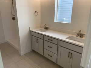 Bathroom with vanity, walk in shower, and tile patterned flooring