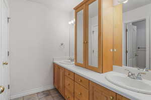 Full bathroom with twin sinks, and a linen closet.